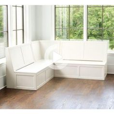 a white bench sitting in front of a window next to a wooden floor and windows