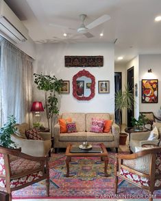 a living room filled with lots of furniture next to a wall mounted mirror and potted plants