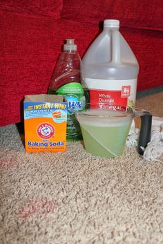 ingredients for baking soda sitting on the floor next to a red couch with a bottle of vinegar