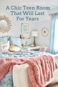 a white bed with pink and blue comforter in a bedroom next to a window