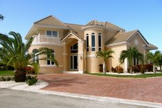 a large house with palm trees in front of it and a driveway leading to the entrance