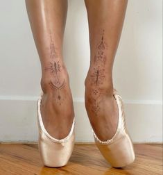 a woman's legs with tattoos on them and her ballet shoes in the foreground