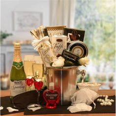 a gift basket with champagne, chocolates, and other items on a table in front of a window