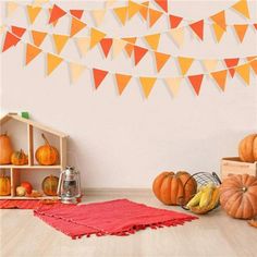 a room with pumpkins and other decorations on the floor in front of a white wall