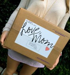 a woman holding a cardboard box with the word love moon written on it