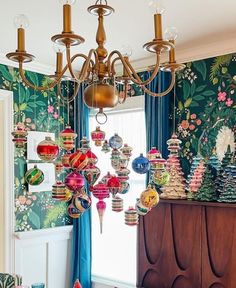 a chandelier hanging from the ceiling in a room with colorful wallpaper and curtains