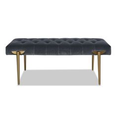 an upholstered bench with gold legs and a black velvet seat pad on it