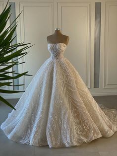 a wedding dress on display in front of a plant