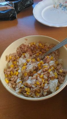 a bowl filled with rice and corn on top of a table