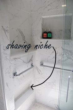 a bathroom with white marble and black lettering on the shower wall that says shaving niche