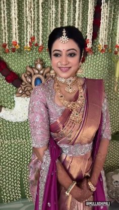 a woman in a pink and gold sari posing for the camera with her hands on her hips