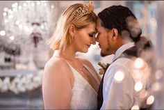 a bride and groom standing close together in front of a chandelier at their wedding