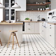 two stools in the middle of a kitchen with white cabinets and black and white floor tiles