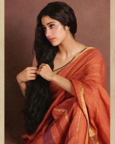 a woman with long black hair wearing an orange sari