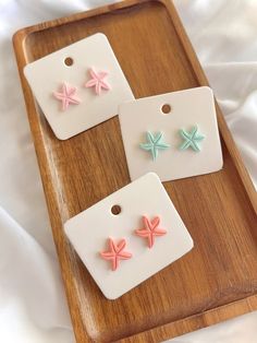 three different colored starfish earrings on a wooden tray