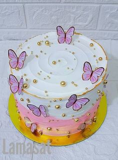 a multi layer cake decorated with pink butterflies and gold beads, on a yellow plate