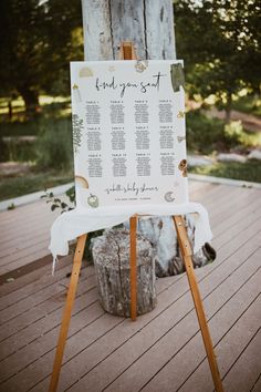 a wooden easel with a calendar on it sitting in front of a tree trunk