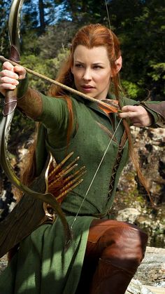 a woman dressed in green is holding a bow and arrow