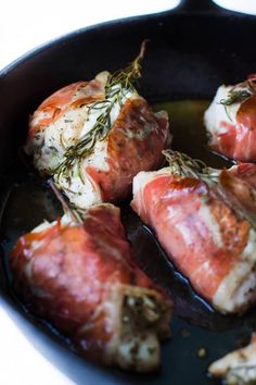 some meat is cooking in a skillet on the stove with herbs and seasoning