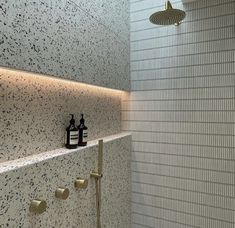 there is a shower head in the corner of this bathroom with black and white speckles on the walls