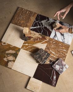 several different types of marbles on the floor with one hand reaching for something in the middle