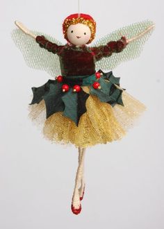 a christmas ornament with a doll on it's body and holly decorations