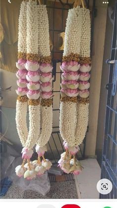 two rows of macaroni hanging from hooks in front of a door with pink and white macaroni's attached to it