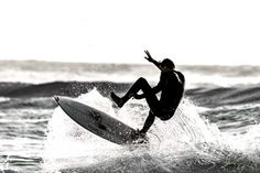 a man riding a surfboard on top of a wave in the ocean at sunset