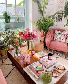 a living room filled with pink furniture and lots of flowers on top of the coffee table