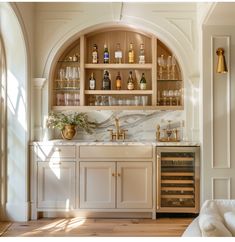 a kitchen filled with lots of bottles and glasses on top of a wooden cabinet next to a sink