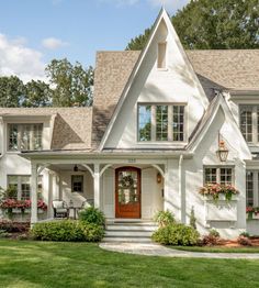 a white house with red front door and two story windows on the side of it