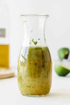 a pitcher filled with green liquid sitting on top of a counter next to other ingredients