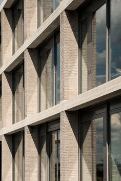 the side of a building with many windows on each floor and sky in the background