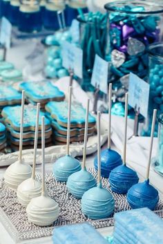 there are many blue and white desserts on the table with candy sticks in front of them