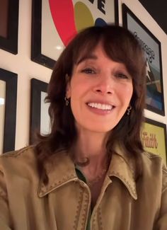 a woman smiling in front of pictures on the wall