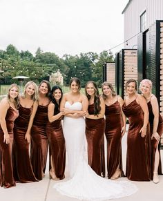 a group of women standing next to each other wearing brown dresses and one woman in a white dress