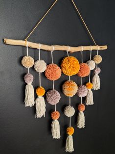 a wall hanging made out of yarn and pom poms on a wooden stick