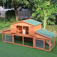 a wooden chicken coop with green roof and two large windows on the side of it