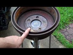 a hand is pointing at an old rusted metal sink