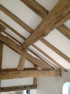 an old wooden ceiling with exposed beams in a room that has white walls and wood flooring