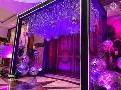 the entrance to a building with purple lights and disco balls hanging from it's ceiling