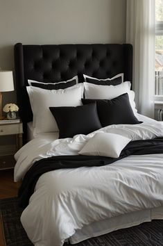 a bed with white and black pillows in a bedroom next to a window on top of a rug