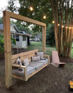 a couch sitting under a wooden arbor with lights hanging from it's sides and trees in the background