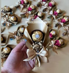 a hand holding a chocolate bouquet in front of many other candies on a table