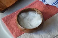 a wooden bowl filled with white substance on top of a pink napkin next to a cutting board