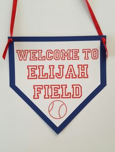 a welcome sign hanging from the side of a white wall with red and blue trim