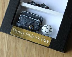 a soccer ball and purse in a shadow box with happy father's day written on it