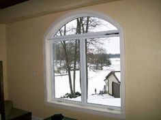 an open window in a living room with snow on the ground and trees behind it