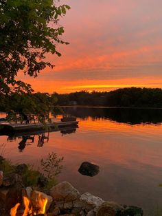 there is a fire pit in the middle of the water with boats on it at sunset