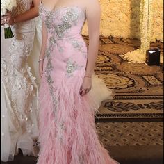 two women standing next to each other in formal dresses and one is wearing a feathered dress